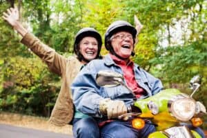 Retired couple riding a moped while driving to hunt for their perfect retirement destination